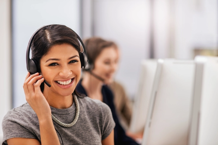 Customer service representative wearing a headset smiling while assisting apartment clients in South Florida, supporting